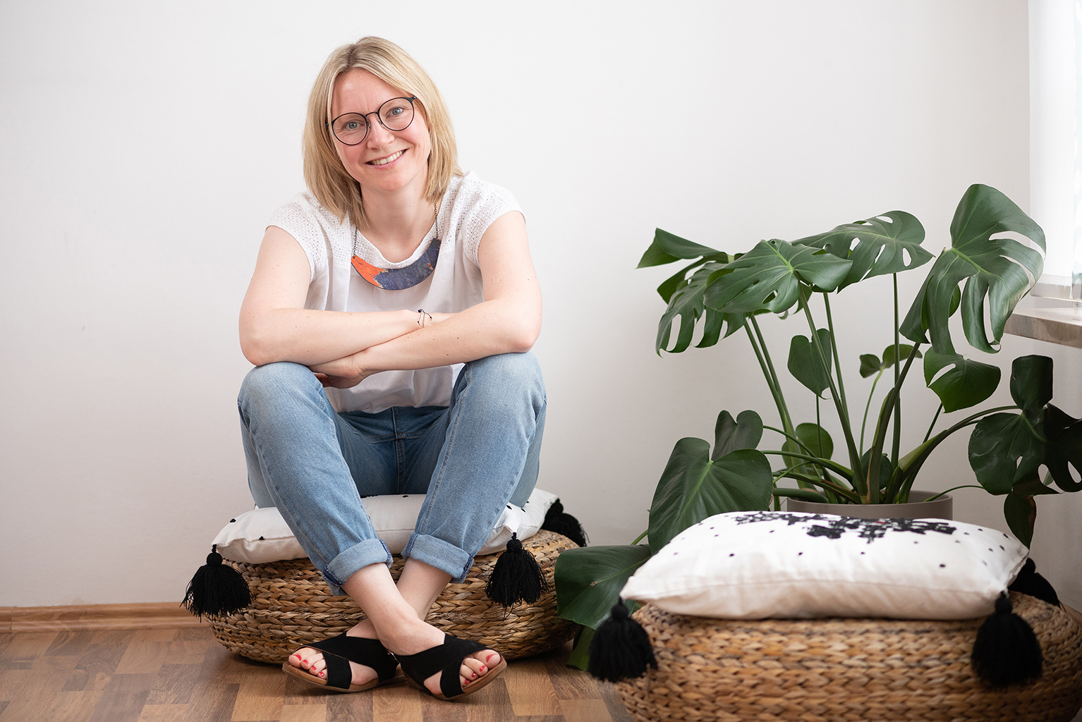 Katarina Müller | sitzend auf einem Korbkissen im Praxisbüro