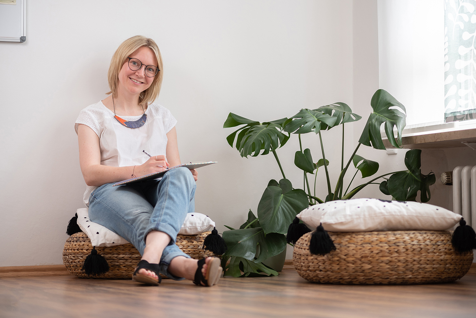 Katarina Müller | sitzend auf einem Korbkissen mit Unterlagen