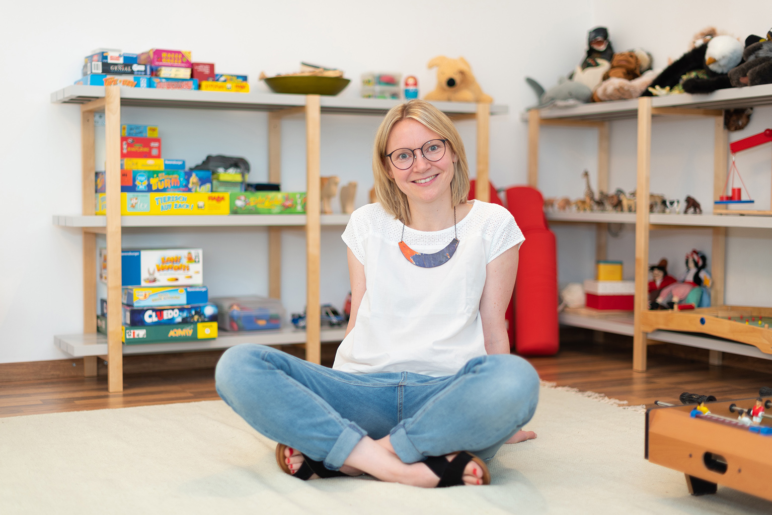 Katarina Müller | sitzend auf Teppich im Therapieraum